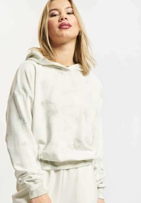 Kremfarget hettegenser med avslappet passform, utstyrt med tie-dye-mønster, ribbestrikkede mansjetter og kant. Myk stoff, egnet for hverdagsbruk.