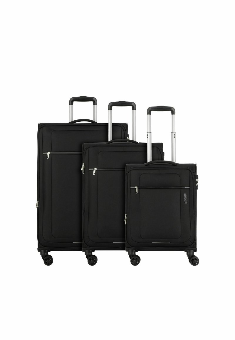 Three black suitcases in varying sizes, made of fabric with smooth texture, featuring zippered pockets and retractable metal handles.