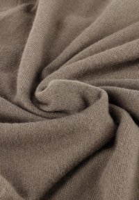 Hellbraunes Strickgewebe mit einer weichen, glatten Textur, das ein Wirbelmuster zeigt und eine leicht dicke, gemütliche Erscheinung hat.