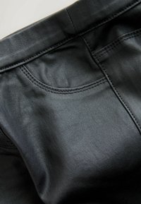 Svarta läderbyxor med en slät textur, som har en subtil glans, rundade ficka-sömmar och en klassisk slim fit-design.