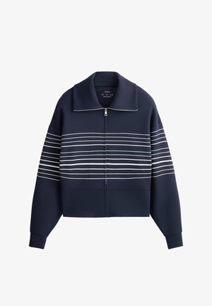 Tmavomodrá bunda na zips so širokým golierom a horizontálnymi bielymi pruhmi cez hruď a rukávy, s dlhými manžetovými rukávmi.