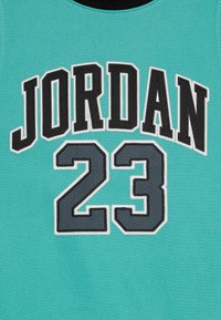 Türkiissinine särk, millel on mustvalge kaarjas kiri "JORDAN" üle "23" hallis toonis, tekstuuriga kangast viimistlus.