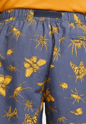 Herreshorts i mørkeblåt stof med et guld insektmønster. Elastisk talje og sidelomme for funktionalitet.