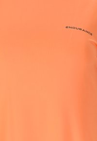 Kirkas oranssi urheilupaita, jossa on musta "ENDURANCE" logo tulostettuna ylärintaan tiiviiseen kankaaseen.