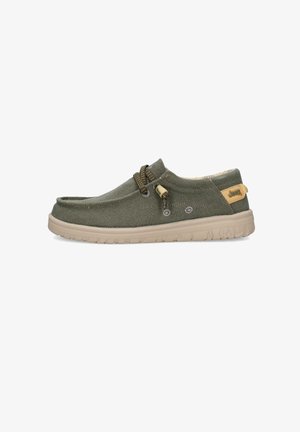 Zapato casual de tela verde oliva tipo slip-on con suela beige, cordones elásticos tipo bungee y una pequeña etiqueta con el logotipo de Jeep en tono marrón claro en el talón.