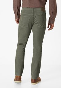 Green corduroy pants with patch pockets, featuring a back yoke, and paired with brown leather shoes. Texture appears soft and durable.