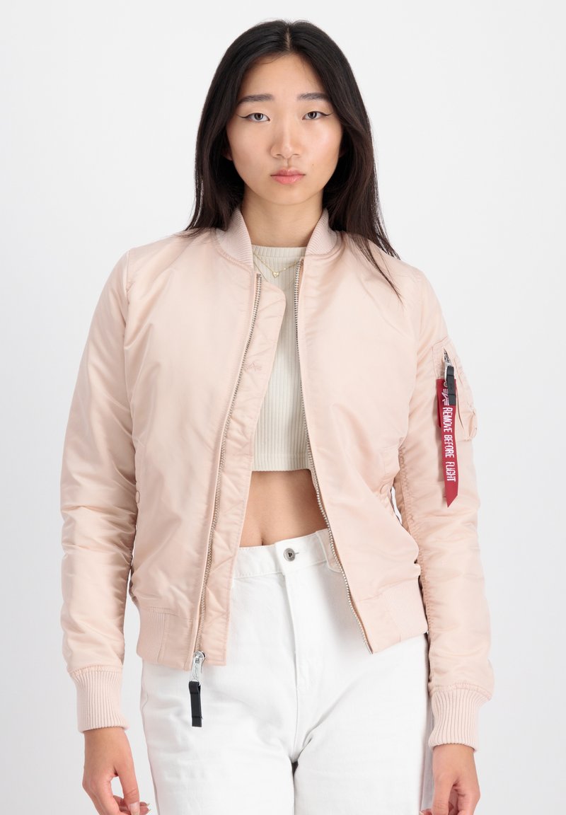 Helle rosafarbene Bomberjacke mit gerippten Bündchen und Saum, durchgehendem Reißverschluss und einem Stoffetikett mit roter Beschriftung auf dem linken Ärmel.