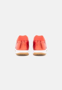 Ténis atléticos vermelhos com material superior refletor, colarinho acolchoado e entressola branca; sola de borracha de goma para tração.