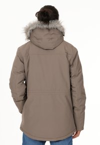 Brun isoleret jakke med hætte af kunstpels, med lynlås foran, sidelommer og en let udvidet kant.