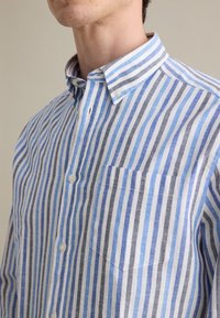 Camicia button-up con righe verticali blu e grigie, in misto cotone-lino, colletto alla francese, tasca singola sul petto e bottoni bianchi.