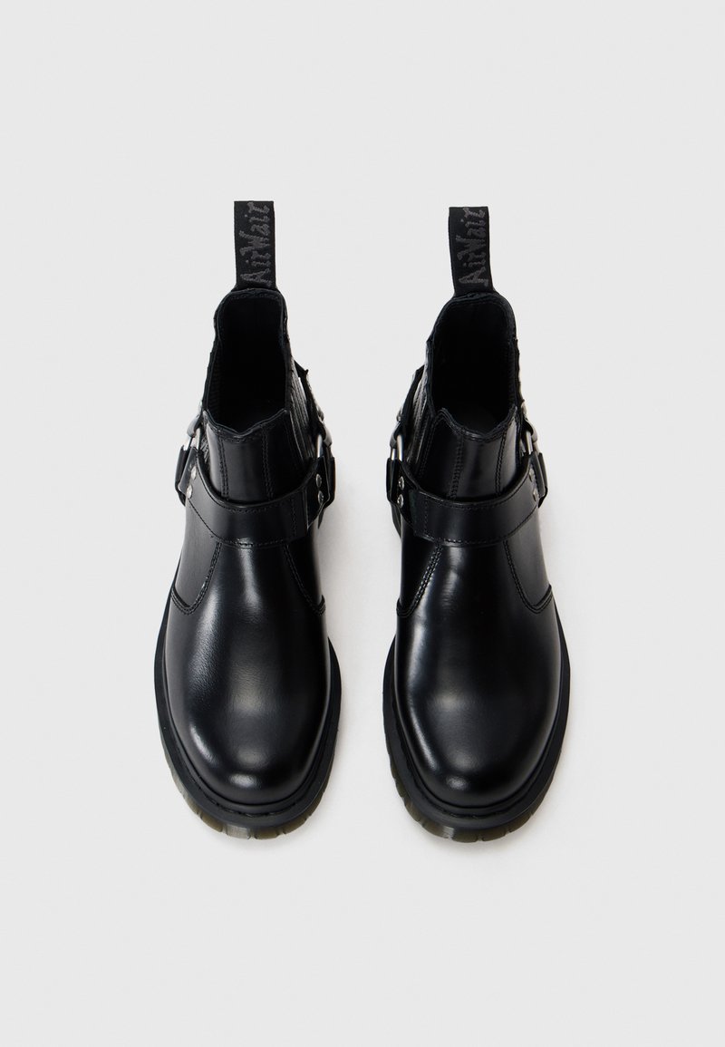 Bottines en cuir noir avec une finition lisse, dotées d'une sangle et d'un détail de boucle. Bout arrondi et semelle basse texturée.
