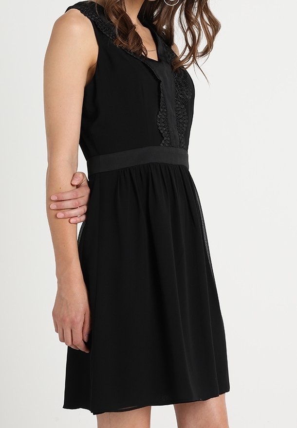 Černé šaty s krajkovým lemem kolem výstřihu a přiléhavým pasem, s rozšířenou sukní a bezrukávovým designem. Hladká textura látky.