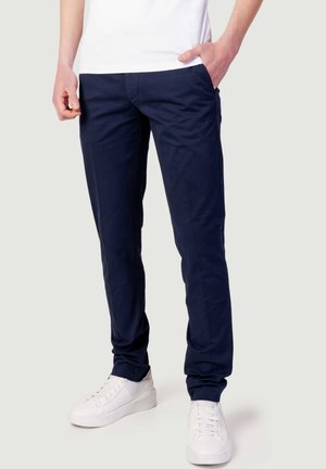 Chinos blu navy con un design slim fit, realizzati in tessuto di cotone leggero. Presentano tasche anteriori e sono abbinati a sneaker bianche.