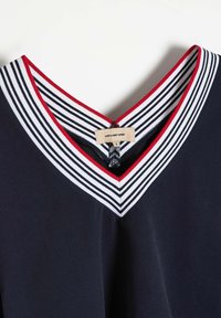 Granatowa bluzka z dekoltem w serek, z paskowanym kołnierzykiem w białym i czerwonym kolorze. Metka z napisem "diverse" i rozmiar "S." Gładka tekstura, sportowy fason.