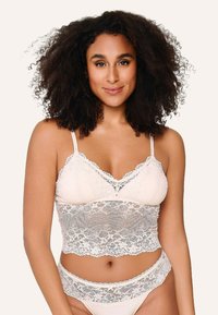 Blonde bralette med justerbare stropper, i en beige farve, med bølgede kanter og et tætsiddende design, der fremhæver blonderdetaljerne.