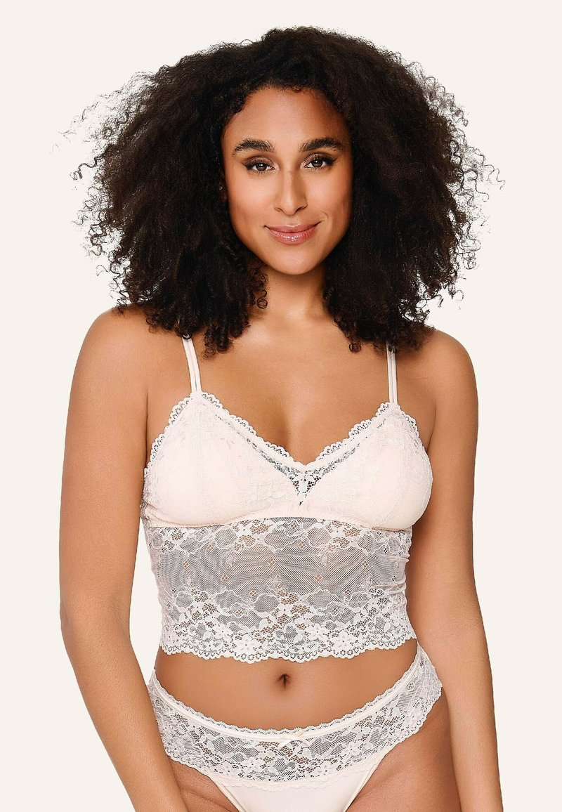 Blonde bralette med justerbare stropper, i en beige farve, med bølgede kanter og et tætsiddende design, der fremhæver blonderdetaljerne.