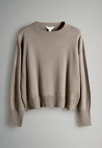 Beige trui gemaakt van een zacht materiaal, met een geribbelde ronde hals, brede mouwen en geribbelde boorden en zoom.