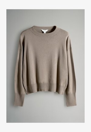 Beige neulepaita, valmistettu pehmeästä materiaalista, jossa on resoroitu pyöreä pääntie, leveät hihat sekä resoroidut hihansuut ja helma.