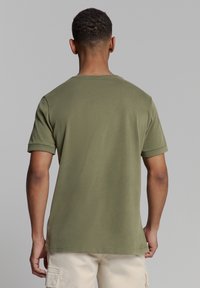 Olijfgroene t-shirt met korte mouwen, gemaakt van zacht katoen, met een klassieke ronde hals en opgerolde mouwen, met een gladde textuur.
