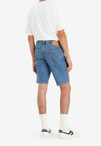 Blå denimshorts med rak skärning, med en läderpatch bak och två bakfickor. Matchas med vita strumpor och sneakers.