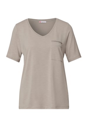 Jasno beżowa koszula z krótkim rękawem, z dekoltem w serek i małą kieszonką po lewej stronie, z delikatnymi detalami teksturalnymi.