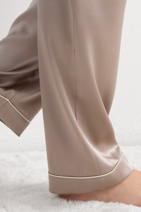 Satijnen beige pyjamabroek met een gladde textuur, voorzien van een witte rand aan de zoom en een losse, relaxte pasvorm.