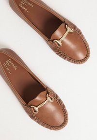Braune Lederloafers mit gesticktem Design und goldfarbenen Hardwareakzenten. Flache Sohle und runde Schuhspitze. Texturierte Innenseite.