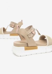 Beige sandals with a breathable mesh toe, smooth leather straps, a thick white platform sole, and gold accents. Logo on the side.