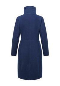 Manteau long bleu marine à col montant, en tissu texturé ; présente un logo au col et une coupe ajustée avec des manches longues.