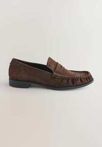 Bruine suède instappers met een ronde neus, slip-on ontwerp en decoratieve stiksels. Lage, platte zwarte rubberen zool. Geen zichtbare hardware.