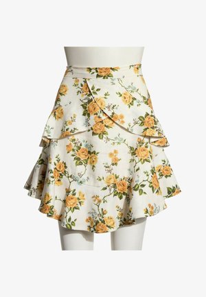 Jupe portefeuille blanche à motifs floraux avec roses jaunes et feuilles vertes, avec des volants superposés et une silhouette évasée.