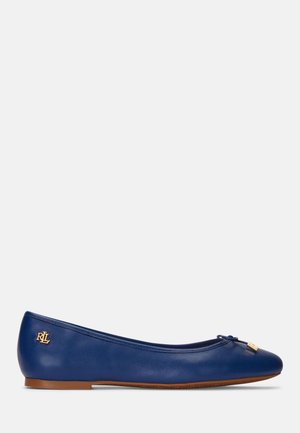 Navy blauwe leren ballerina met kleine strik en goudkleurig logo detail, en een bruine platte zool.