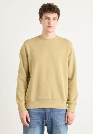 Light brown sweatshirt made of cotton, featuring a round neck and long sleeves. Small logo on the chest. Paired with blue distressed jeans.