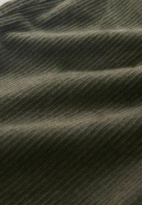 Strukturiertes Stoffgewebe in dunklem Olivgrün, mit feinen, parallelen Rippenstreifen, die visuelle Tiefe und Weichheit erzeugen.