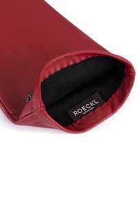 Borsetta in pelle rossa con esterno liscio e morbido rivestimento interno nero. Presenta un'etichetta con "ROECKL MÜNCHEN" all'apertura.