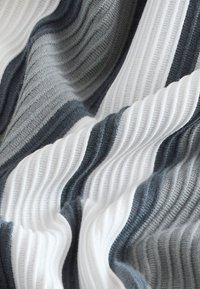Gebreide stof met golvende strepen in donkergrijs, lichtgrijs en wit. Getextureerd oppervlak met afwisselend gladde en geribbelde patronen.