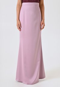 Langer, hellrosa Rock aus glattem Stoff, mit hohem Bund und fließendem Design, das bis zum Boden reicht, mit einem schlichten und eleganten Schnitt.