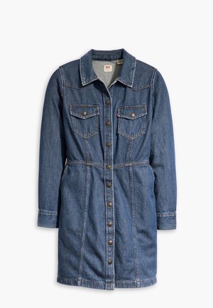 Robe en denim bleu mi-longue avec manches longues, fermeture à boutons sur le devant, deux poches poitrine à rabats, et col de chemise.