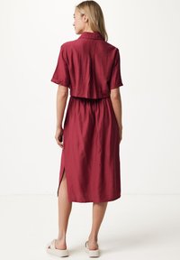 Abito bordeaux con maniche corte, colletto e vita elastica. Presenta spacchi laterali e una vestibilità rilassata. Realizzato in tessuto leggero.