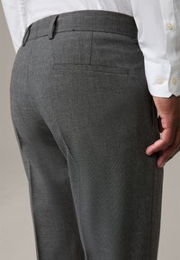 Grijze op maat gemaakte broeken met een gestructureerde afwerking, met een rechte snit, achterzak en riemlussen, gecombineerd met een witte dress shirt.