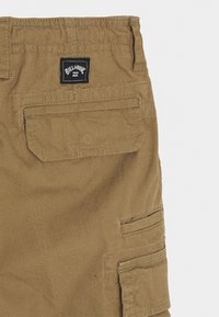 Khaki szorty cargo wykonane z wytrzymałej tkaniny; posiadają wiele kieszeni, wyszywane akcenty oraz czarną metkę z napisem "Billabong" na tylnej części pasa.