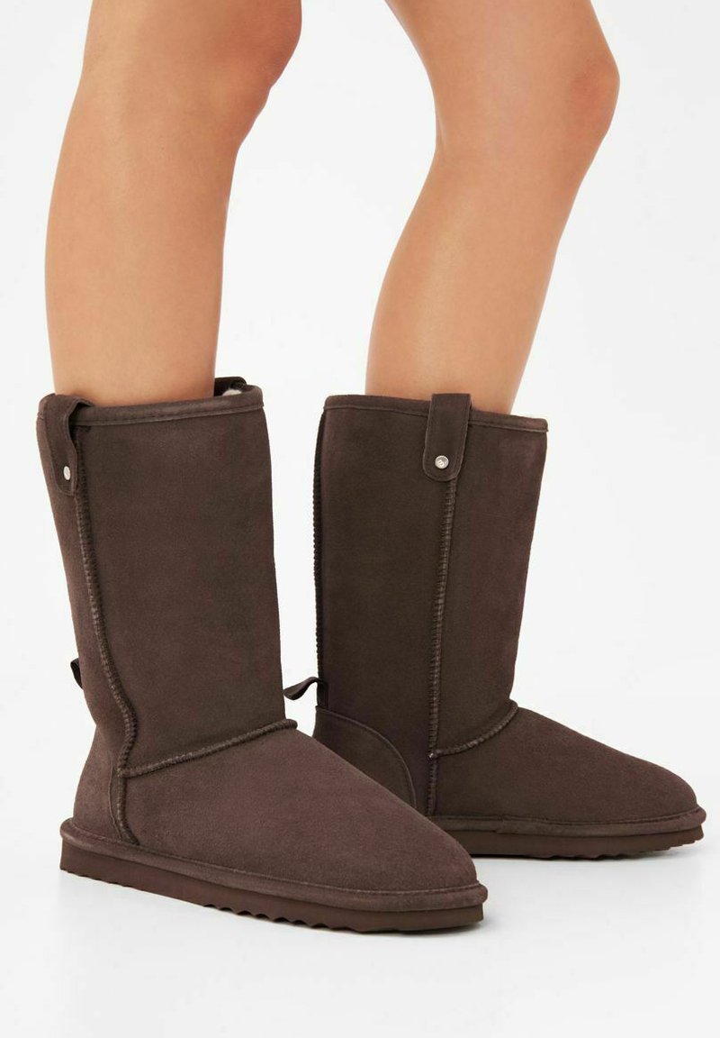 Bruine suède enkellange laarzen met een zachte textuur, ronde neus en een zijknopdetail. Ontworpen voor warmte en comfort.