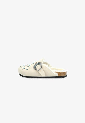 Zuecos de mujer sin hebillas en ante beige con adornos en azul y plateado, forro de piel de oveja y plantilla de corcho. Suela de goma negra duradera.