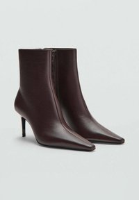 Botines de tacón alto marrones, con punta afilada, material de cuero suave, cierre de cremallera en la parte delantera, tacón de aguja delgado, diseño elegante.