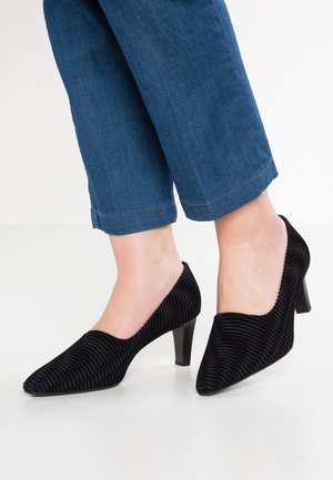 Sorte høje hæle med ribbet tekstur, spids tå og en slank, stablet hæl, båret med cropped blå denimbukser.