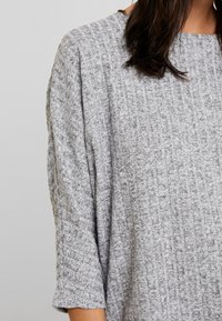 Top grigio a maglia con un motivo testurizzato, scollo ampio e maniche a tre quarti. Tessuto morbido con una vestibilità ampia.