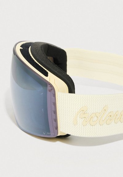 Óculos de esqui com lente curva de tom azul, almofadado em espuma preta e uma correia elástica creme com texto em escrita cursiva em relevo.