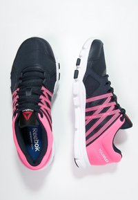 Mustat ja vaaleanpunaiset urheilukengät verkko- ja synteettisellä materiaalilla. Ominaisuuksiin kuuluu valkoinen pohja, kerroksellinen muotoilu ja nauhoitusjärjestelmä, joka takaa tukevan istuvuuden.