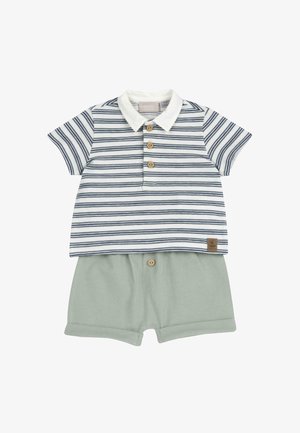 Polo shirt à manches courtes rayé en blanc et bleu marine, doté de boutons en bois. Associé à un short vert clair, également avec des accents de boutons en bois.
