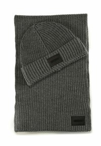 Bufanda de punto acanalado gris oscuro y gorro a juego, ambos con parches rectangulares negros de la marca Hugo.